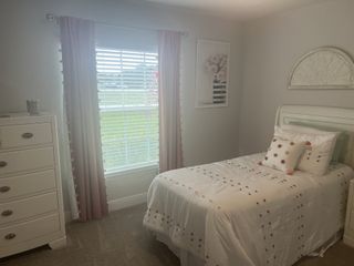 A cozy bedroom featuring a single bed, plush polka-dot bedding, natural light, and elegant decor accents.