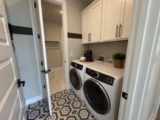 A chic laundry room with patterned tile flooring, white cabinetry, and modern appliances for functional elegance.
