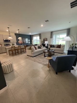 Modern open living area with tiled floors, cozy seating, and a stylish kitchen featuring pendant lighting and barstools.