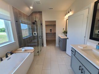 A luxurious bathroom with a freestanding tub, glass shower, dual vanities, and modern lighting.