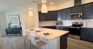 Modern kitchen with sleek navy cabinets, white island, and pendant lighting, creating a chic and functional space.