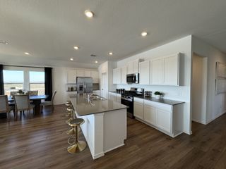 A modern kitchen with sleek countertops, stylish barstools, and a spacious dining area illuminated by natural light.