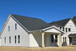 A charming white home with a covered porch in Windsor Crossing by Dream Finders Homes (North Charleston, SC).