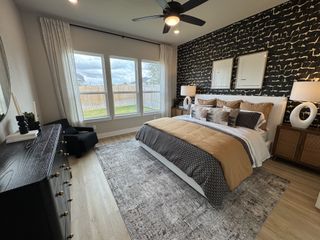 A chic bedroom featuring a bold accent wall, cozy bedding, elegant lamps, and large windows inviting natural light.