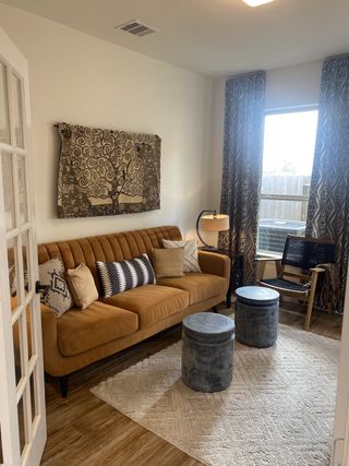A cozy living room with a camel sofa, modern art, patterned curtains, and chic decor accents.