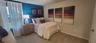 A cozy bedroom with vibrant blue accent wall, modern art, and soft lighting, creating a tranquil and inviting atmosphere.