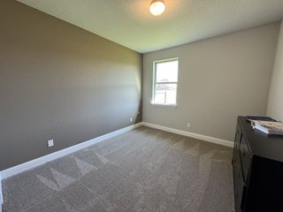 A cozy room with soft carpet, neutral walls, and a small window providing natural light.