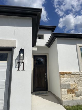A sleek modern home with a contrasting stone accent in The Crest at Elm Creek by Tirol Homes (San Antonio, TX).