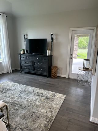 A cozy living area with a sleek entertainment console, rustic accents, and a stylish rug on dark hardwood floors.