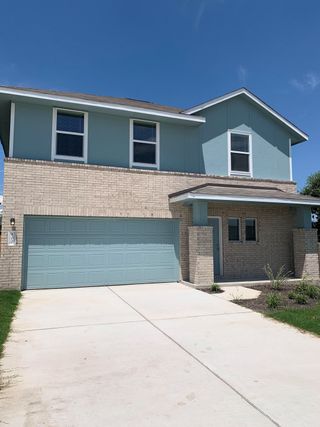 Street view A modern blue and brick home with a sleek garage in Eastwood at Sonterra: Cottage Collection by Lennar (Jarrell, TX).
