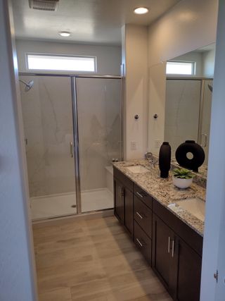 Elegant bathroom with granite dual vanity, modern fixtures, and a spacious glass-enclosed shower.