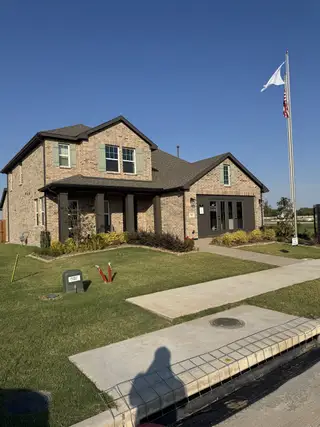 A charming brick home with manicured lawn in Meadow Park by Ashton Woods (Melissa, TX).
