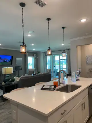 A modern kitchen with pendant lighting, sleek countertops, and a cozy attached living area perfect for entertaining.