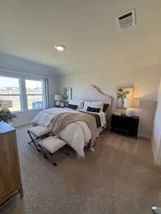 A cozy bedroom with a plush bed, soft lighting, and elegant decor in a serene, carpeted setting.