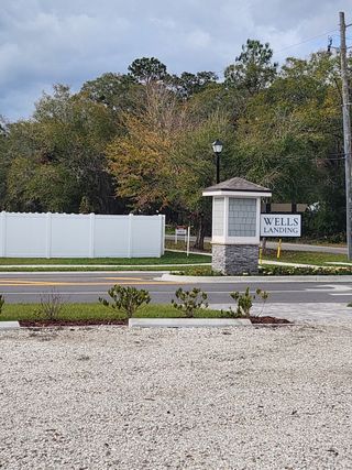 Entrance to Wells Landing by Centex, featuring a landscaped setting with trees and a welcoming sign in Jacksonville, FL.