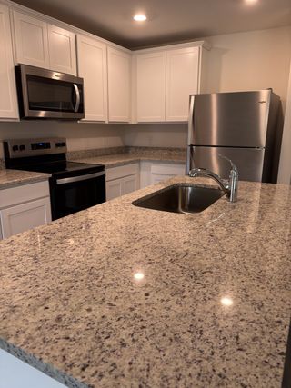 Modern kitchen featuring granite countertops, stainless steel appliances, and elegant white cabinetry.
