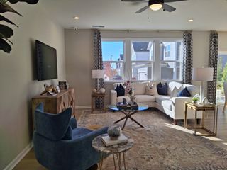 Model Home A cozy living room featuring a white sectional, patterned rug, modern accents, and natural light for a welcoming atmosphere.