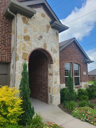 Street view A charming brick and stone home with vibrant landscaping in Elevon by D.R. Horton (Lavon, TX).