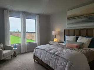 A cozy bedroom featuring a plush bed, soft lighting, and large windows with serene outdoor views.