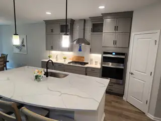 Model Home A modern kitchen with a marble island, sleek grey cabinets, and stainless steel appliances.