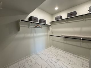 A spacious walk-in closet with sleek shelving, marble-patterned tile flooring, and modern storage boxes.