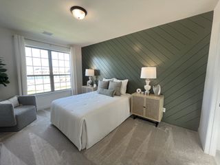 A spacious primary suite with a bay window, elegant feature wall, and cozy seating area.