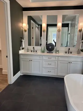 Model Home A chic bathroom featuring a white double vanity, elegant mirrors, and modern lighting with sleek fixtures.