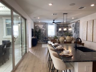 A modern open-concept kitchen and living area featuring a large island, stylish mural, and cozy seating.