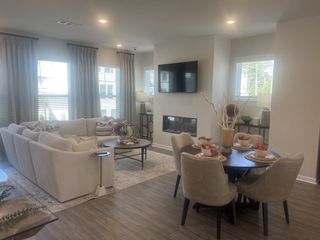 A cozy living-dining space with a plush sectional, sleek TV, and elegant dining set on rich wood flooring.