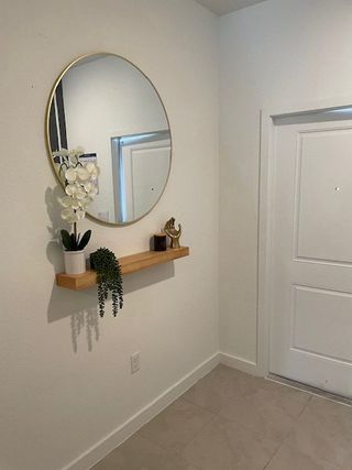 Model Home A welcoming entryway with a round mirror, elegant floating shelf, and minimalist decor.