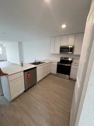 Model Home A sleek kitchen featuring white cabinets, quartz countertops, and a stainless steel range and microwave.