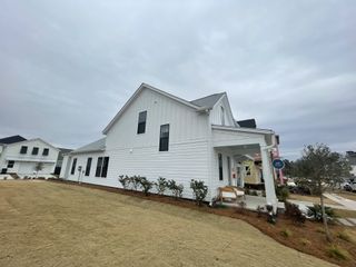 A charming white home with a gabled roof and landscaped yard in Nexton - Midtown by DRB Homes (Summerville, SC).