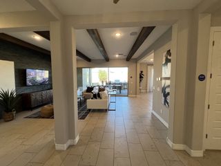 A modern living area with beamed ceilings, tiled floors, sleek furniture, and a large window overlooking a patio.