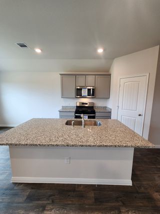 Modern kitchen with granite island, stainless steel appliances, and elegant cabinetry.