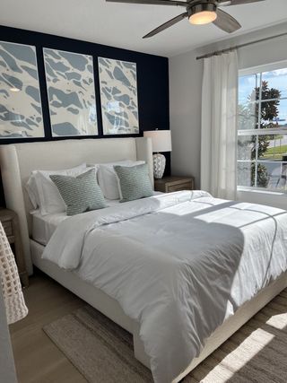 Model Home A cozy bedroom with a plush bed, abstract art, natural light, and light wood accents for a serene retreat.