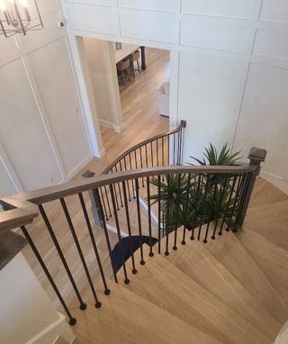 A stylish interior featuring a curved staircase with sleek black railings and wood flooring, leading to an open living space.