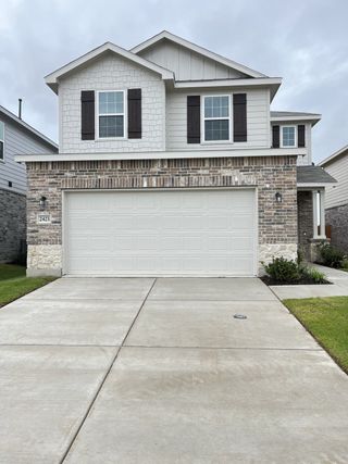 A modern two-story home with brick accents and dark shutters in Ashford Crossing by Centex (Princeton, TX).