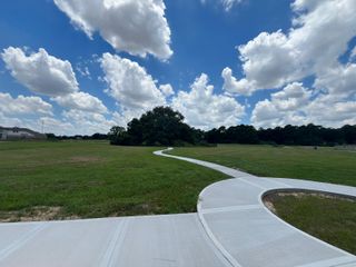 Expansive green space with a winding path in Champions Oak by Long Lake Ltd. (Houston, TX).