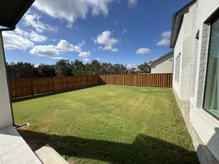 Model Home A spacious backyard with lush grass and a wooden fence in Parmer Ranch - 60' by Westin Homes (Georgetown, TX).