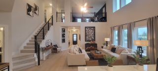 A spacious living area featuring high ceilings, modern artwork, and elegant furnishings with ample natural light.