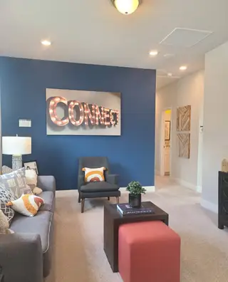 A cozy living room with a bold blue accent wall, modern seating, and decorative lighting spelling "CONNECT."
