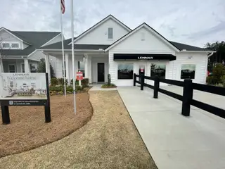 A charming white-paneled home with a manicured lawn in Horizons at Summers Corner by Lennar (Summerville, SC).