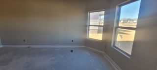 A sunlit room with large windows, unfinished concrete floors, and neutral walls, ready for customization.