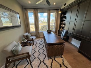 A sophisticated home office with a modern desk, built-in cabinets, and cozy armchairs overlooking a picturesque view.