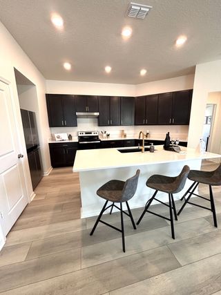 Model Home A modern kitchen with dark cabinets, sleek appliances, and a spacious island with bar seating.