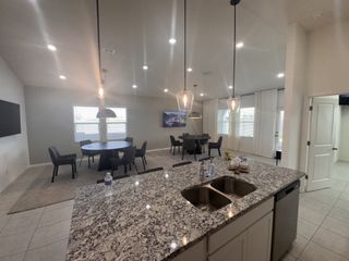 A spacious modern kitchen with a granite island, dual sinks, and stylish pendant lighting opens to a cozy dining area.