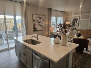 A contemporary open-plan living space with a sleek kitchen island, elegant decor, and large windows offering natural light.