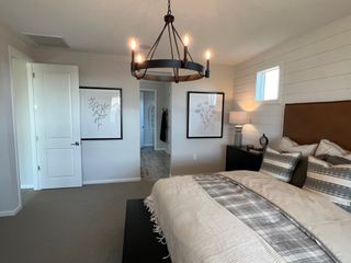 Model Home A cozy bedroom featuring a rustic chandelier, plaid bedding, and elegant artwork, exuding warmth and modern style.
