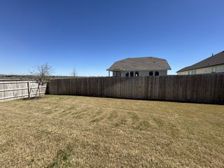 Street view A spacious backyard with a wooden fence under a clear blue sky in The Parklands by Bellaire Homes (Schertz, TX).