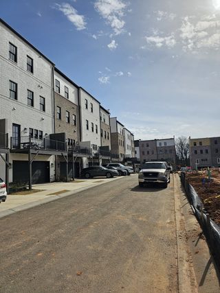 Stylish townhomes with brick facades, modern black accents, and spacious balconies in Skyview On Broad by Kittle Homes (Sugar Hill, GA).